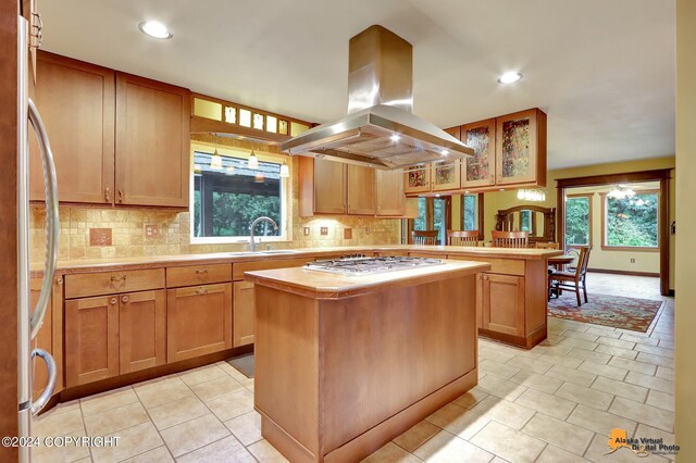 kitchen featuring island exhaust hood, a kitchen island, backsplash, appliances with stainless steel finishes, and sink