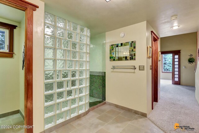 bathroom with walk in shower, a healthy amount of sunlight, and tile patterned floors