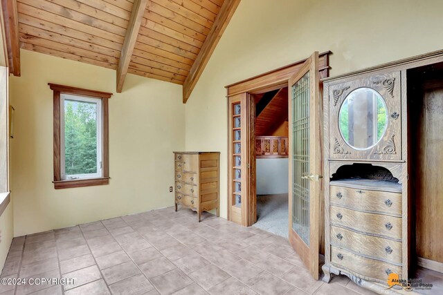 interior space with vaulted ceiling with beams, wooden ceiling, and light tile patterned floors