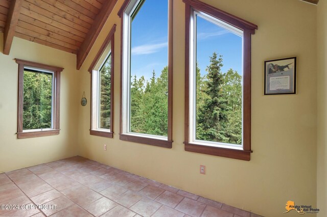 tiled empty room with lofted ceiling, wooden ceiling, and plenty of natural light