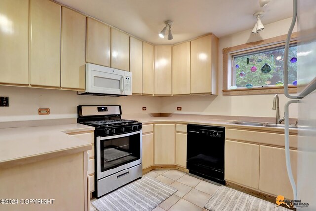 kitchen with black dishwasher, gas range, light tile patterned floors, and sink