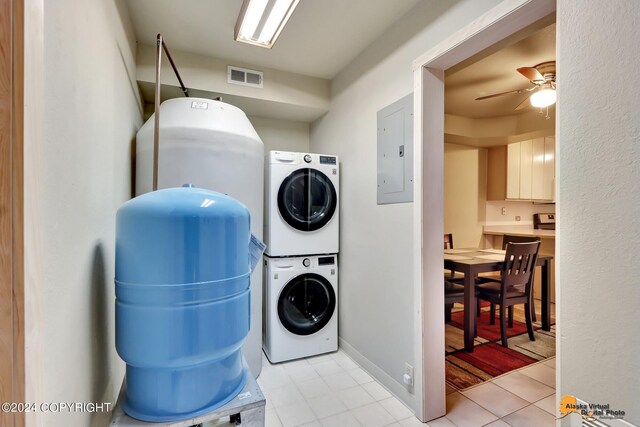 laundry area with light tile patterned floors, electric panel, ceiling fan, and stacked washer and dryer