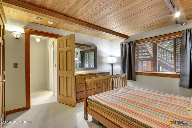 bedroom featuring beamed ceiling, light colored carpet, and wood ceiling