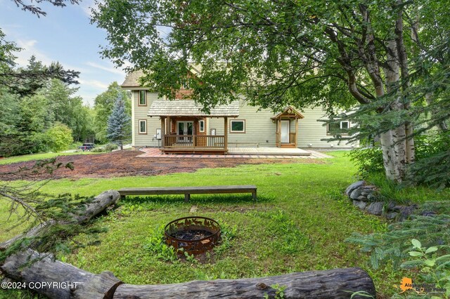 rear view of property featuring a fire pit, a lawn, and a deck