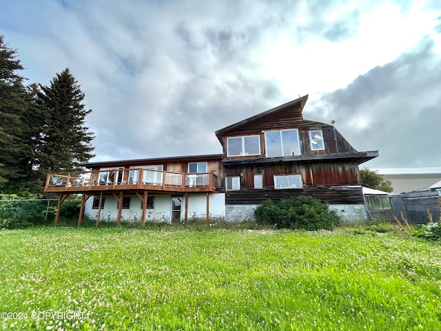 rear view of property with a deck and a lawn