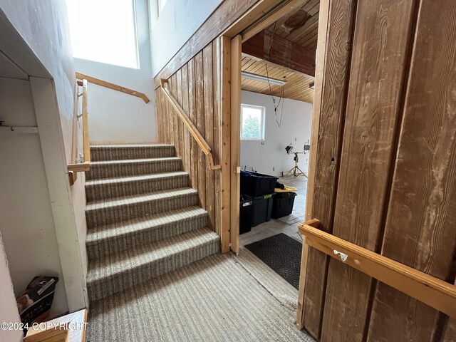 staircase featuring carpet floors, wooden ceiling, and a high ceiling