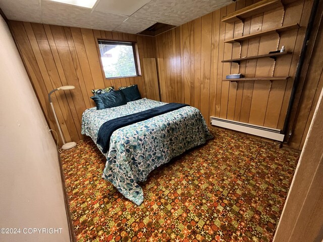 bedroom featuring wood walls and baseboard heating