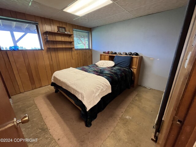 bedroom featuring a drop ceiling and wooden walls