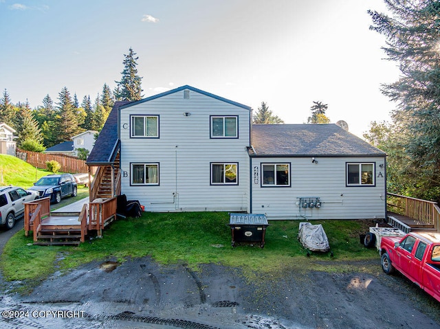 back of house featuring a lawn and a wooden deck