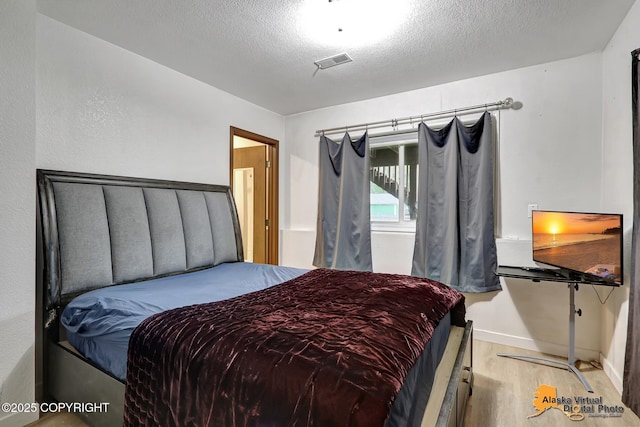 bedroom featuring light wood-type flooring and a textured ceiling