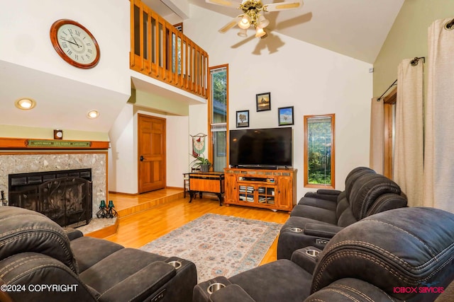 living room with high vaulted ceiling, ceiling fan, a high end fireplace, and light wood-type flooring