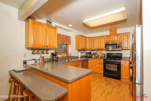 kitchen featuring stainless steel appliances, sink, kitchen peninsula, and light hardwood / wood-style floors