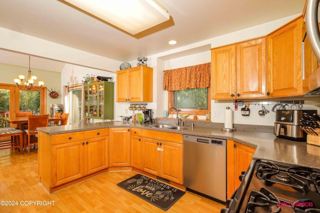 kitchen with black range with gas stovetop, light wood-style floors, a sink, dishwasher, and a peninsula