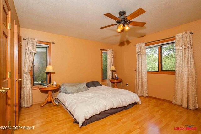 bedroom featuring light wood-type flooring, a textured ceiling, and ceiling fan