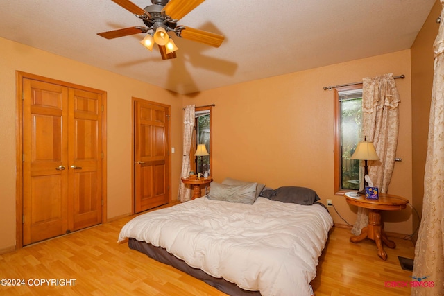 bedroom featuring multiple closets, baseboards, a ceiling fan, and wood finished floors