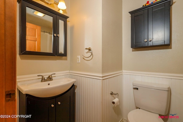 bathroom with a wainscoted wall, toilet, and vanity