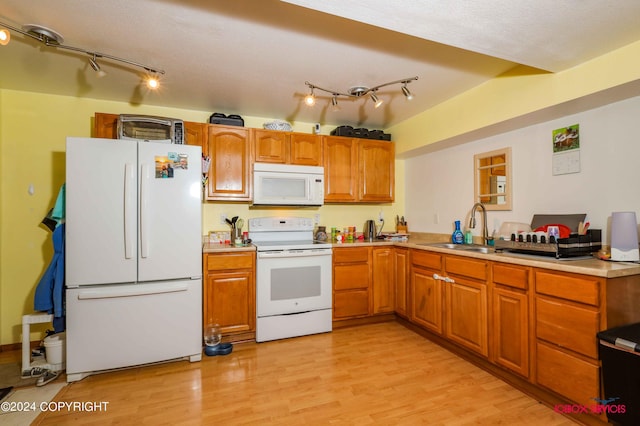 kitchen featuring white appliances, a sink, light wood-style floors, light countertops, and brown cabinets