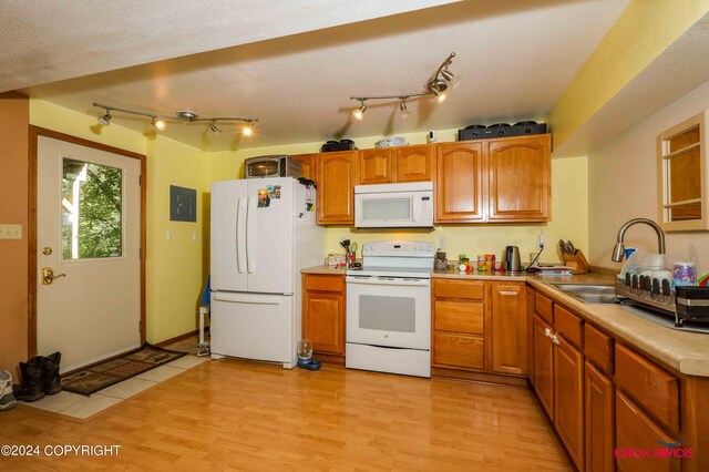 kitchen with track lighting, white appliances, light hardwood / wood-style flooring, a textured ceiling, and sink