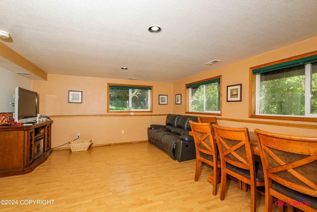 living room featuring visible vents, a textured ceiling, and light wood finished floors