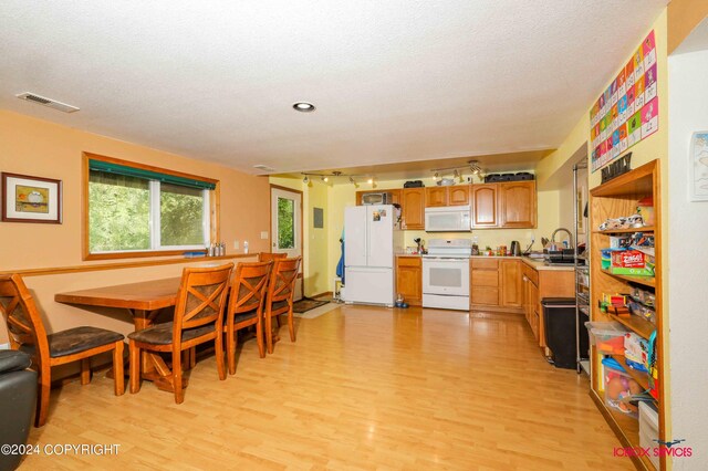 dining room with a textured ceiling, rail lighting, and light hardwood / wood-style floors