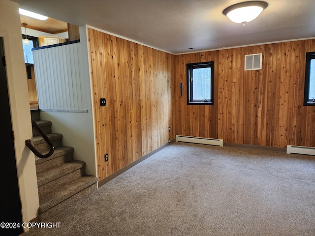 interior space featuring wood walls, carpet floors, and a baseboard heating unit