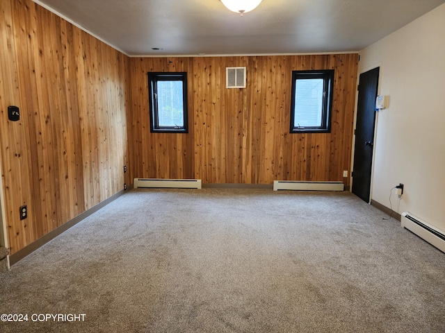 carpeted empty room with baseboard heating and wooden walls