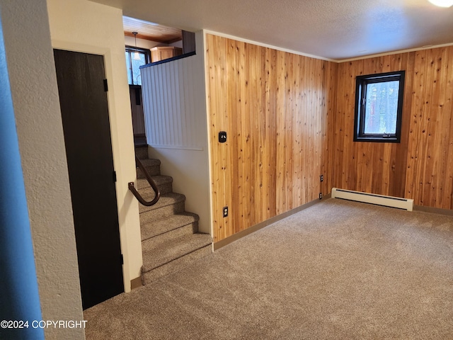 basement featuring carpet flooring, a textured ceiling, baseboard heating, and wooden walls