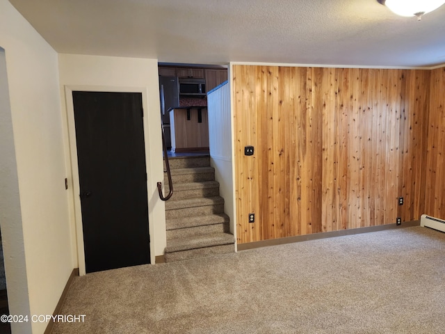 interior space with carpet, wood walls, black fridge, and a textured ceiling