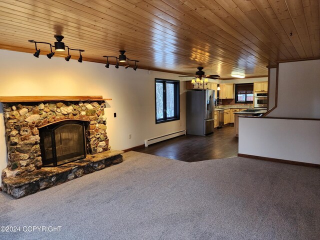 20527 Mark Cir, Chugiak, AK 99567 - unfurnished living room with a baseboard heating unit, dark carpet, plenty of natural light, a stone fireplace, and wood ceiling