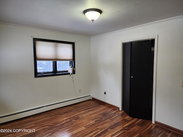 unfurnished room featuring a textured ceiling, dark hardwood / wood-style floors, baseboard heating, and crown molding