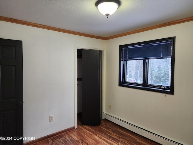 spare room with a textured ceiling, crown molding, dark wood-type flooring, and a baseboard radiator