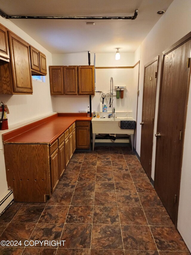 20527 Mark Cir, Chugiak, AK 99567 - kitchen featuring brown cabinetry, dark stone finish flooring, a baseboard radiator, and dark countertops