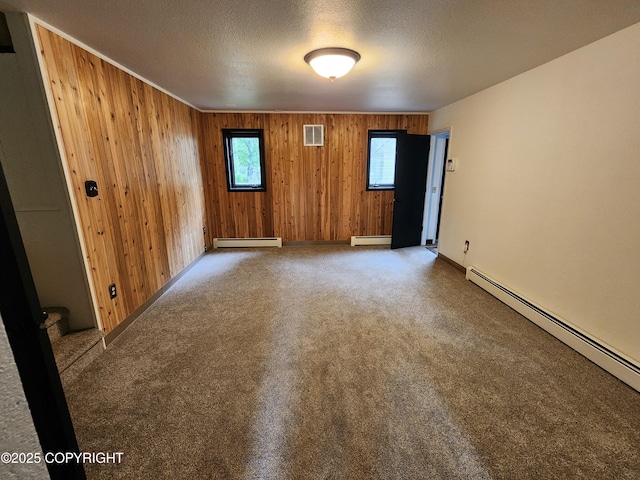 20527 Mark Cir, Chugiak, AK 99567 - empty room featuring baseboard heating, wood walls, a textured ceiling, and carpet flooring