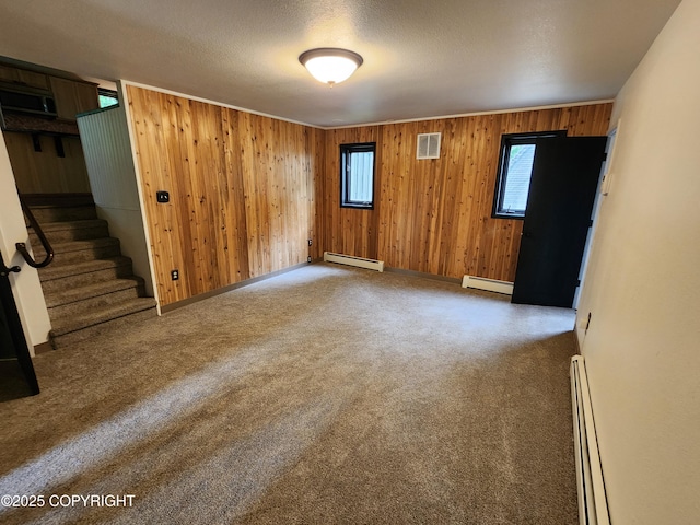 20527 Mark Cir, Chugiak, AK 99567 - spare room featuring a baseboard heating unit, baseboard heating, plenty of natural light, wooden walls, and a textured ceiling