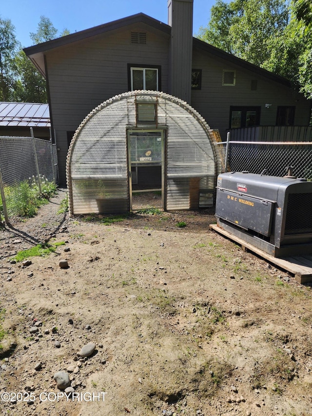 20527 Mark Cir, Chugiak, AK 99567 - rear view of house with a greenhouse, a chimney, and an outbuilding