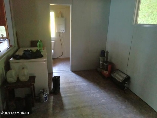 interior space featuring water heater, concrete floors, and a healthy amount of sunlight