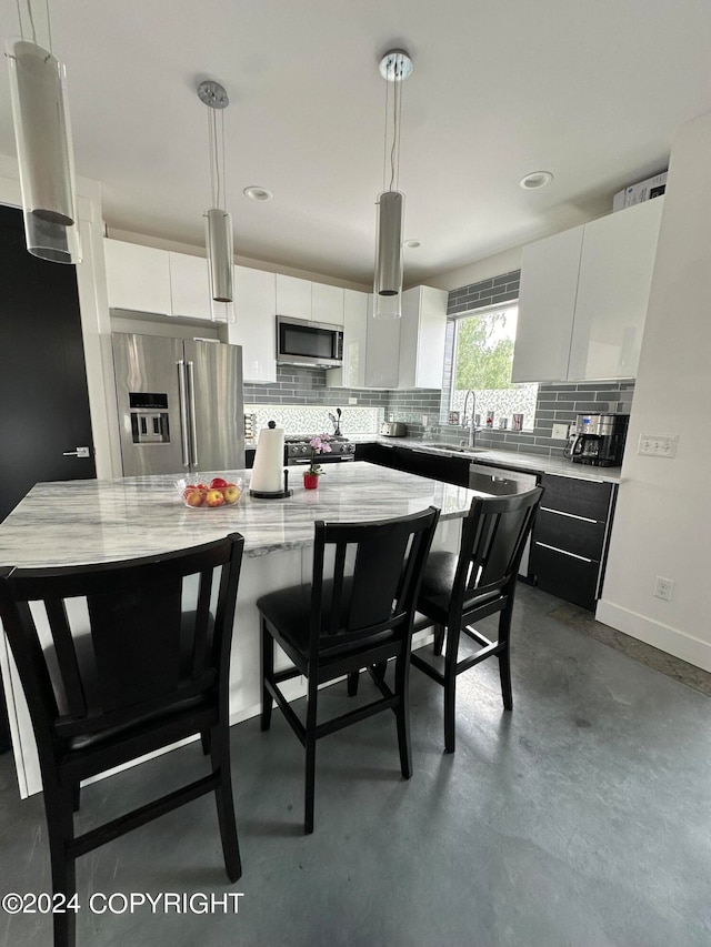 kitchen featuring stainless steel appliances, white cabinets, a kitchen island, and hanging light fixtures