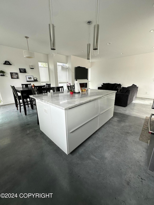 kitchen with light stone countertops, decorative light fixtures, white cabinetry, and a kitchen island