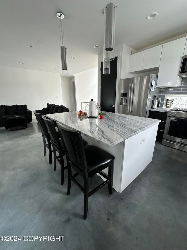 kitchen featuring pendant lighting, a center island, white cabinets, a kitchen breakfast bar, and appliances with stainless steel finishes