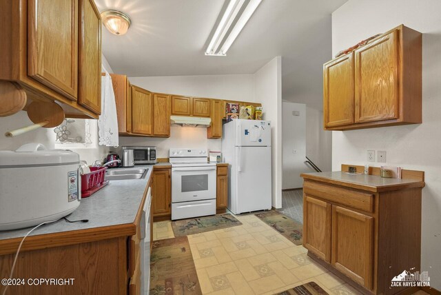 kitchen with white appliances, sink, and vaulted ceiling