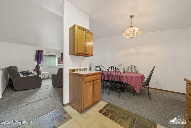 kitchen featuring light carpet, pendant lighting, vaulted ceiling, and a notable chandelier