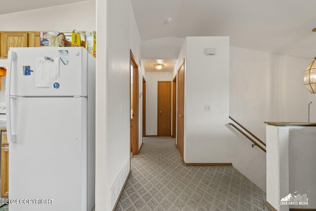 hallway featuring vaulted ceiling and carpet