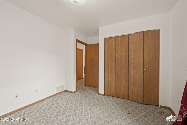 unfurnished bedroom featuring a closet and light colored carpet