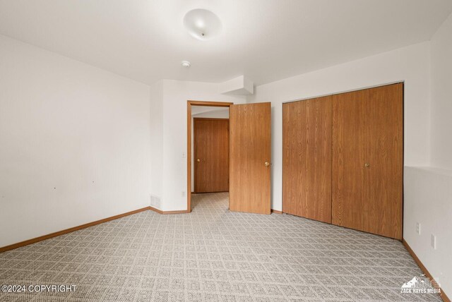 unfurnished bedroom with a closet and light colored carpet