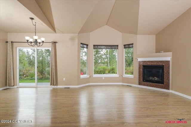 unfurnished living room featuring high vaulted ceiling, plenty of natural light, light hardwood / wood-style floors, and a notable chandelier