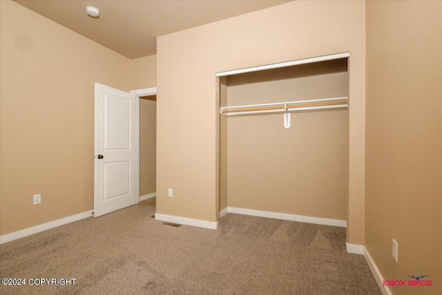 unfurnished bedroom with a closet and light colored carpet