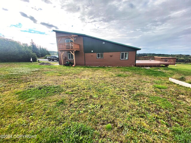 back of property with a wooden deck and a lawn