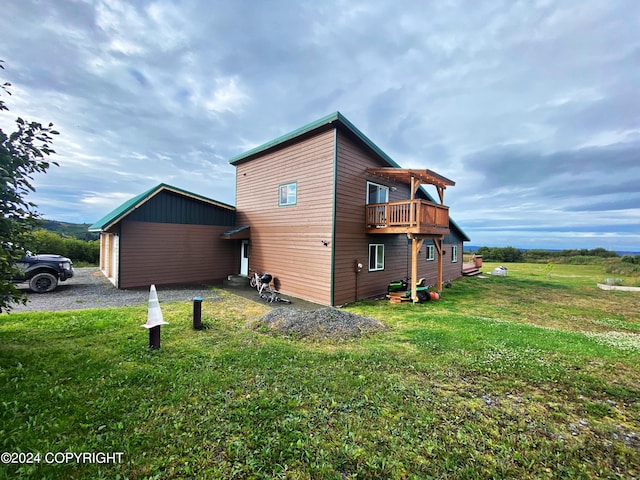 rear view of property featuring a yard and a balcony