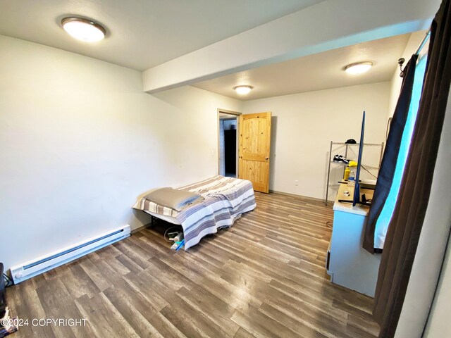 bedroom with hardwood / wood-style floors and a baseboard heating unit