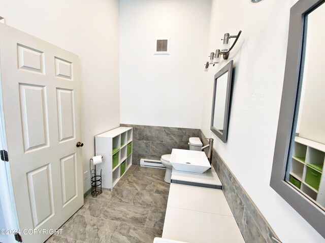 bathroom featuring tile walls, baseboard heating, and toilet